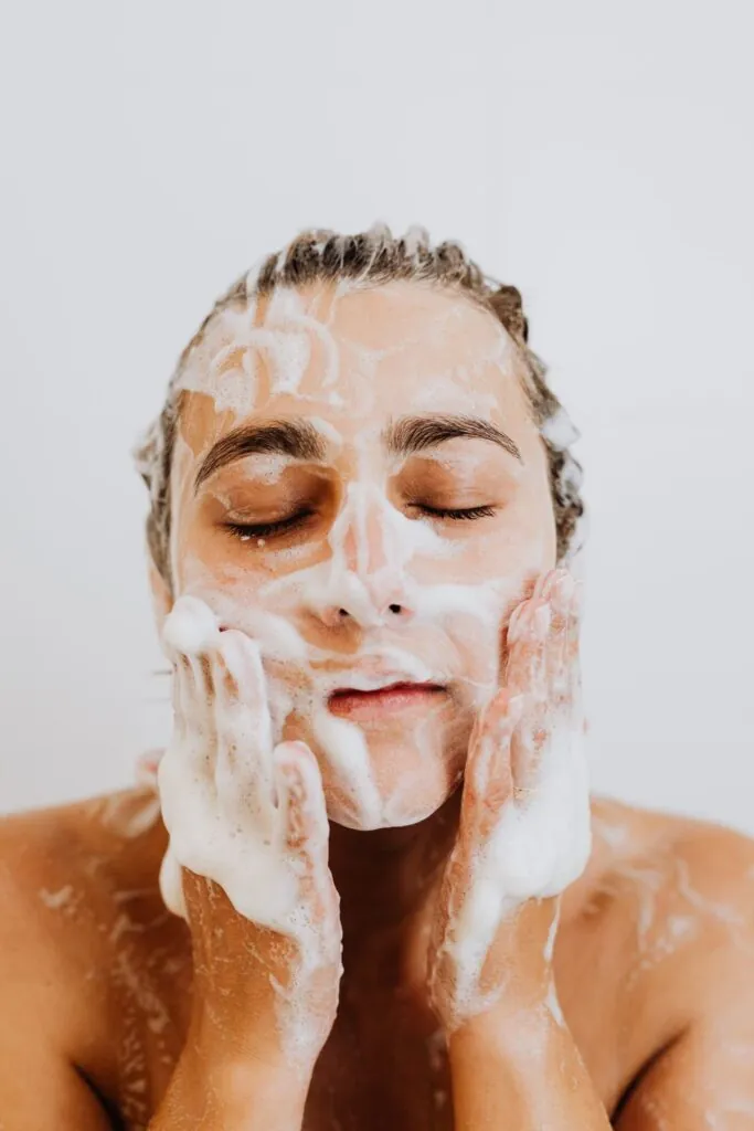 Femme nettoyant son visage avec une mousse